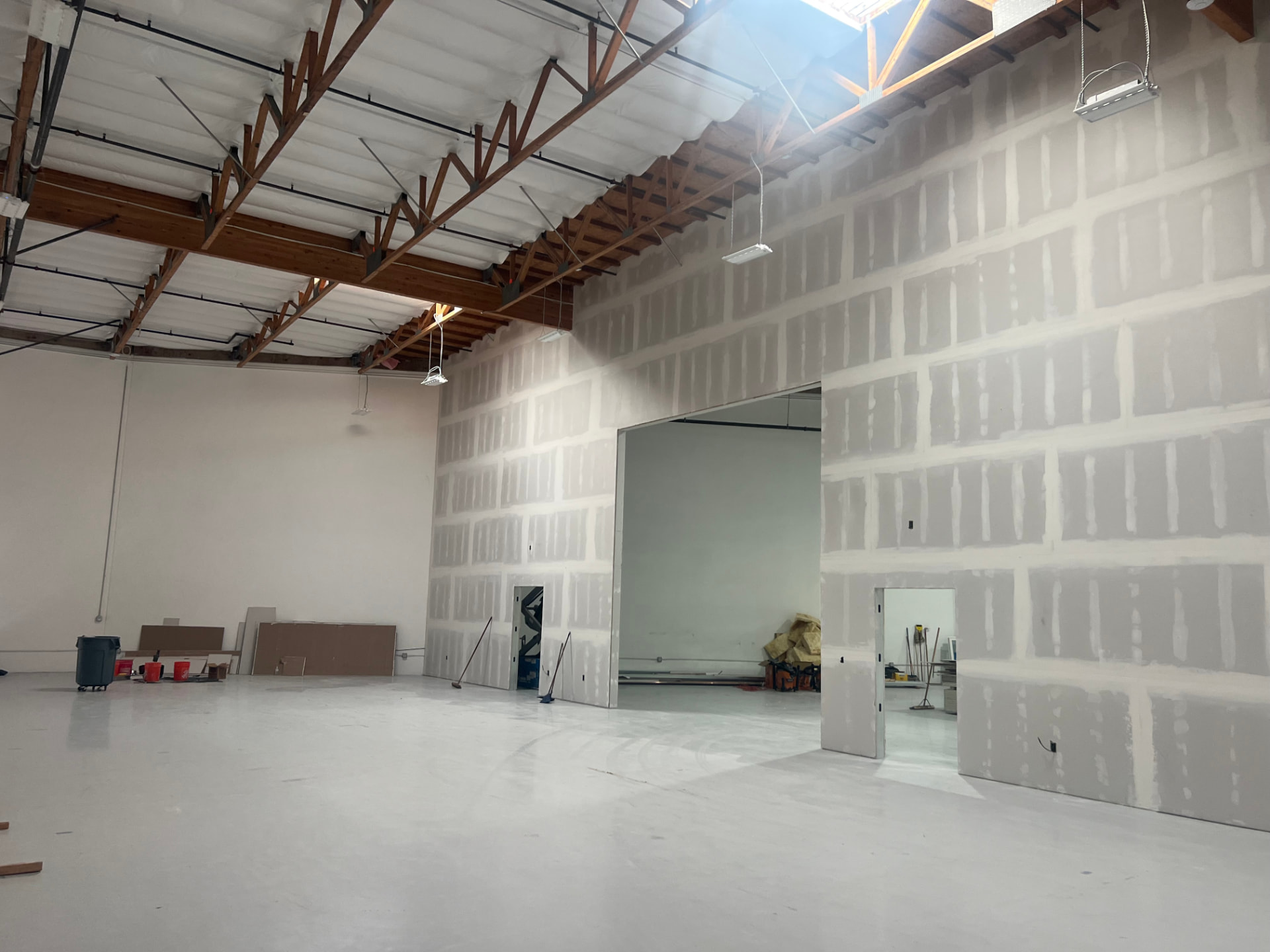 Finished warehouse interior with new drywall walls, framed openings and skylit wood truss ceiling