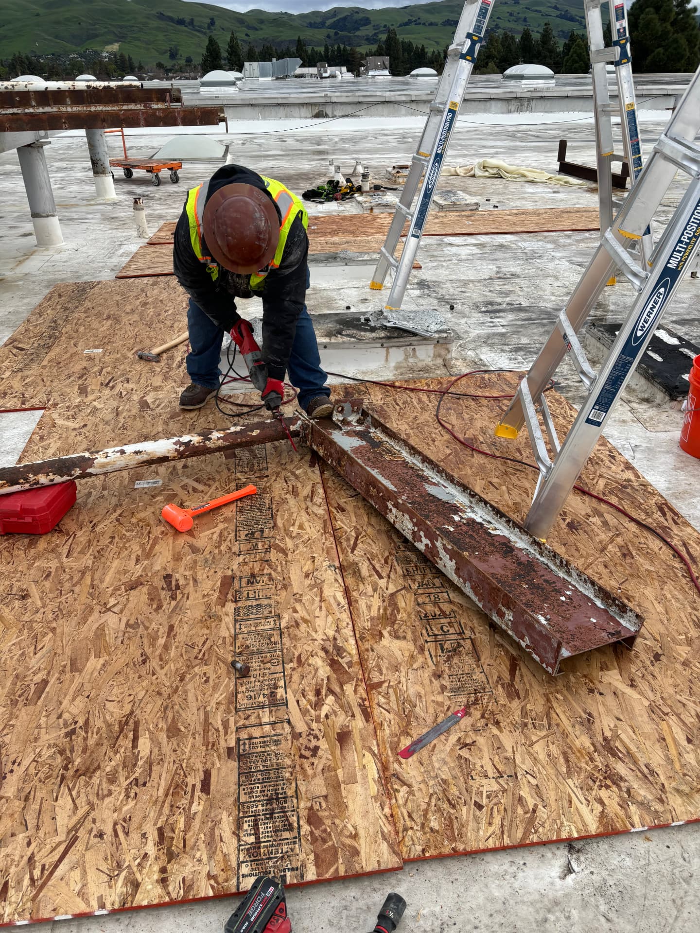Ironworker fastening steel curb supports during a rooftop equipment retrofit